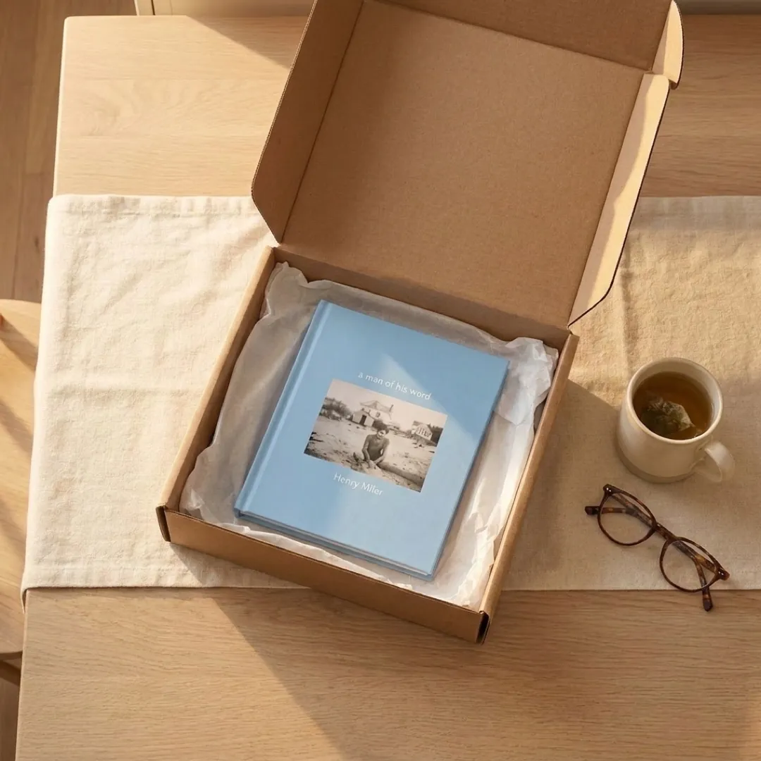 A finished blue hardcover in its opened delivery box on a kitchen table