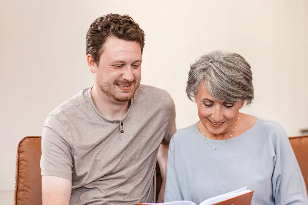 Two family members leaning over the same open page of a finished life story book
